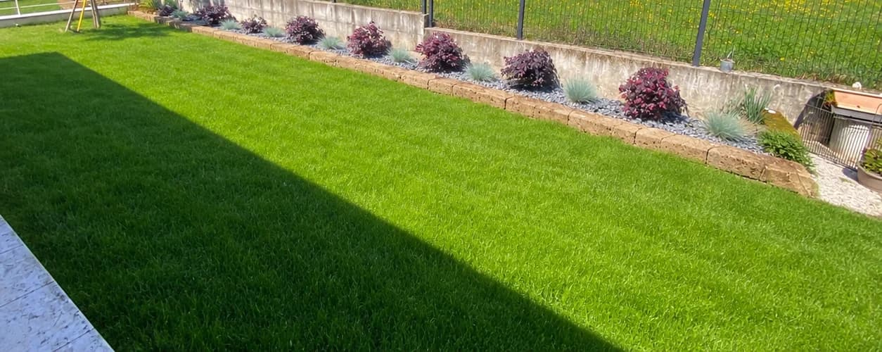 Prato verde e aiuola lungo la recinzione dopo la sistemazione